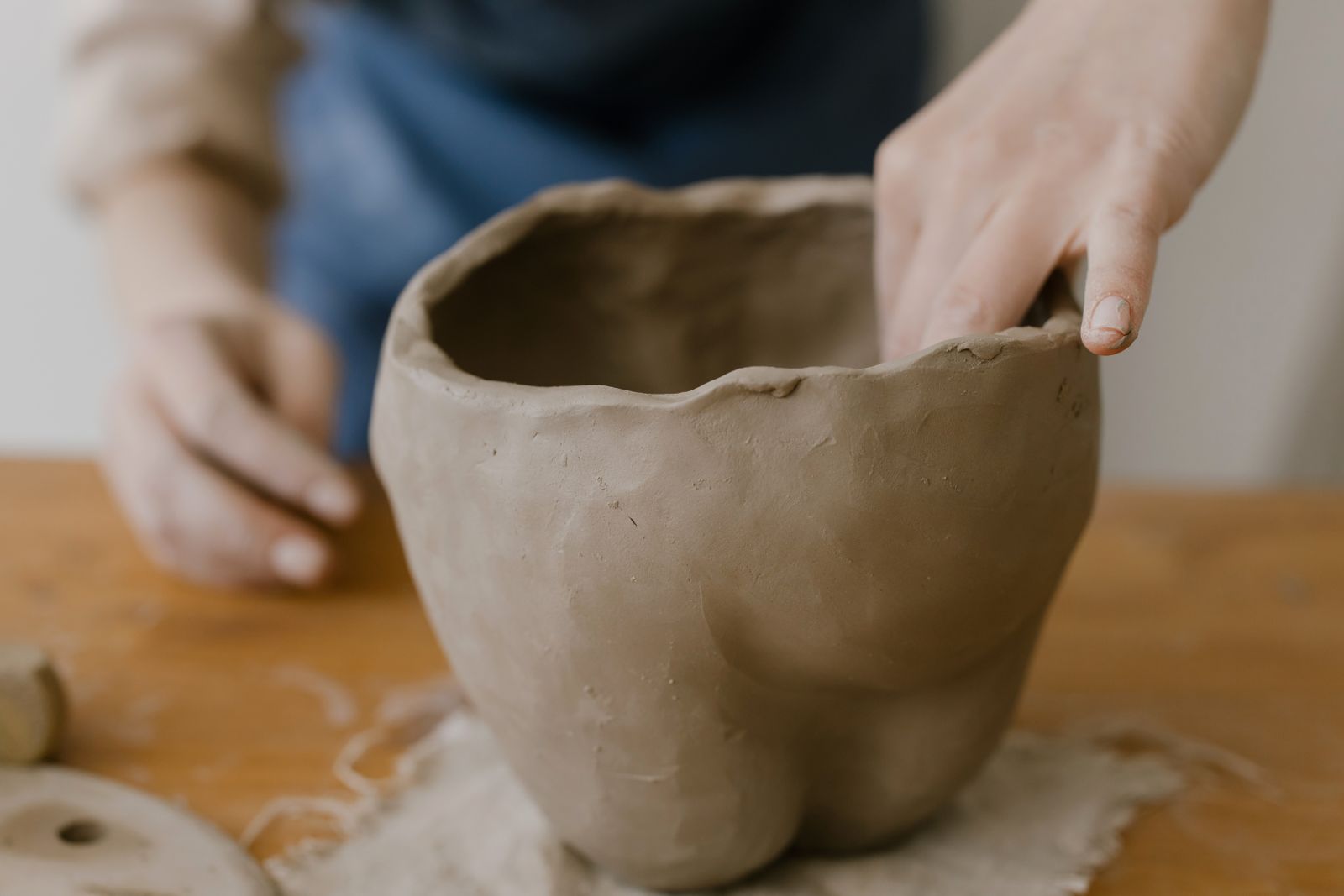 Mains qui façonnent un pot en argile sur une table en bois
