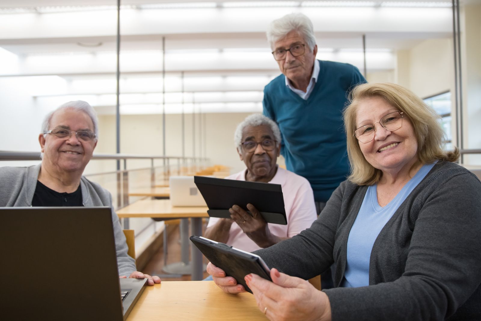 Personnes âgées souriantes apprenant à utiliser une tablette et un ordinateur